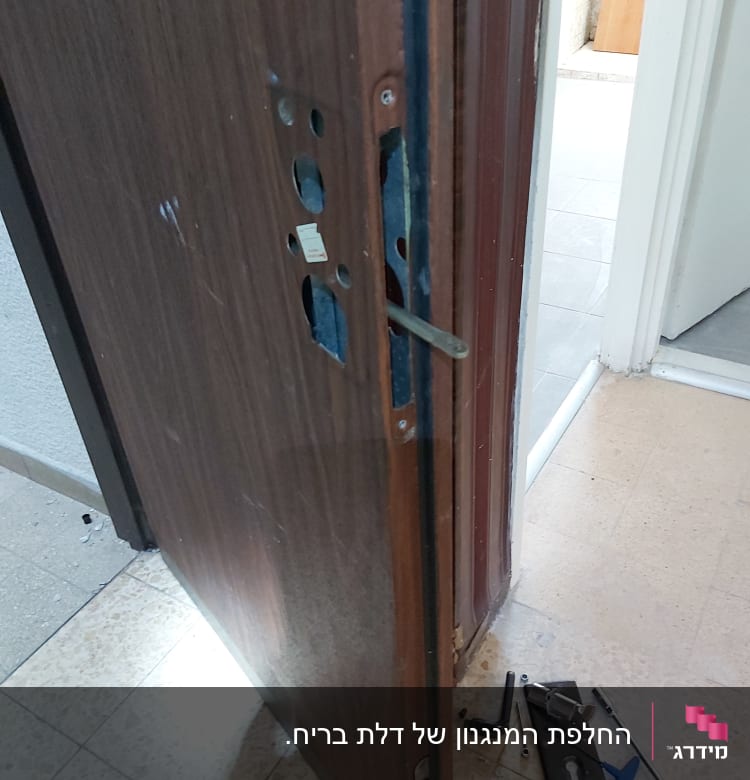 דלת פתוחה עם מנעול מפורק וכלי עבודה על הרצפה